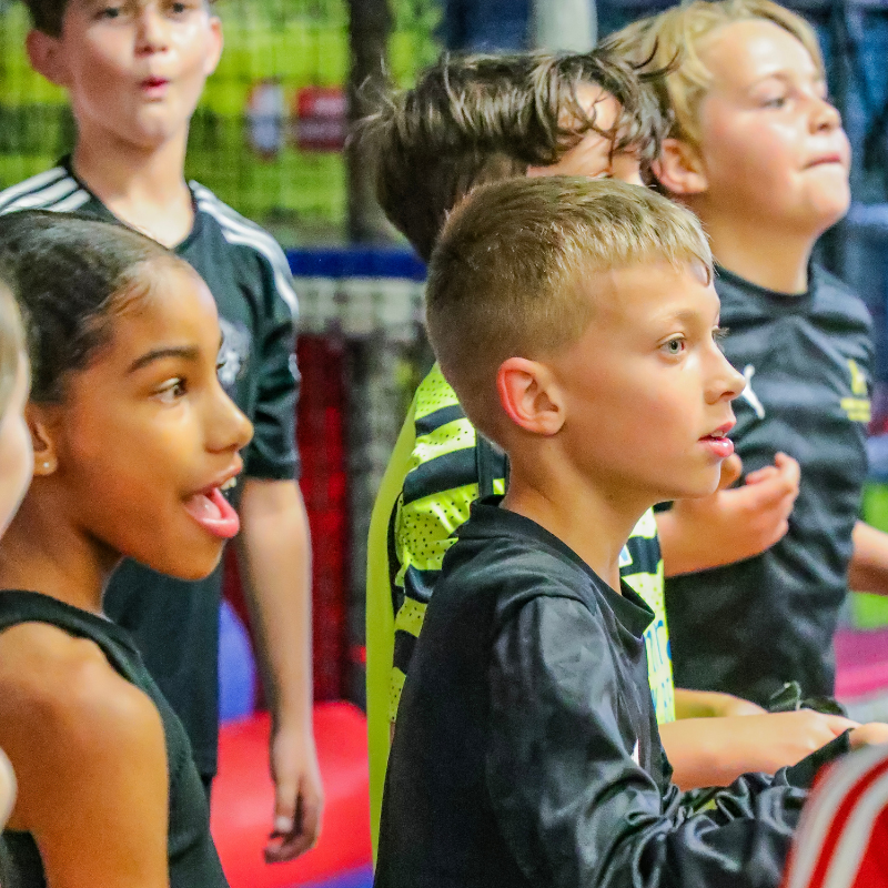 Young kids in black jerseys playing together in soft play frame
