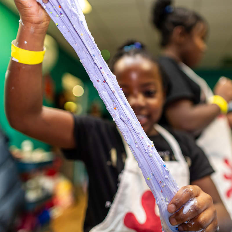 Child playing with stretchy purple slime in a classroom setting