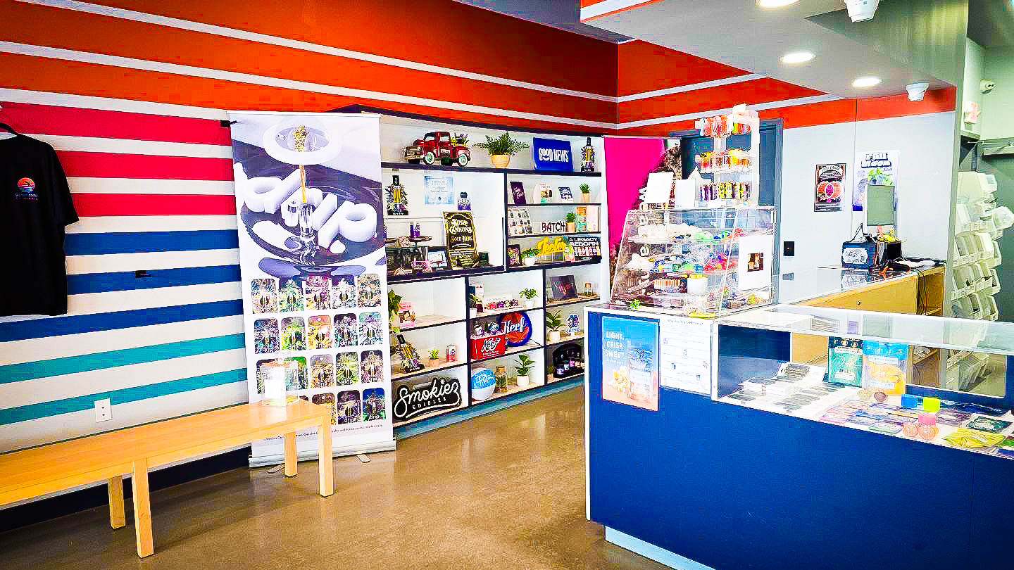 Sunset Coast Provisions cannabis dispensary exterior with modern architectural design and large windows in a lush suburban setting.