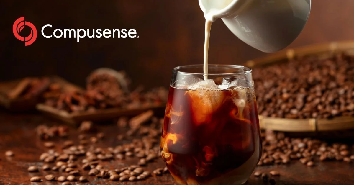 Dark roasted coffee beans with a metal portafilter scoop, warm lighting highlighting the rich brown tones.