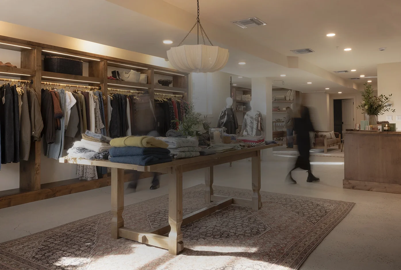 Miro Miro Truckee CA Clothing store interior with wooden racks, folded sweaters on a table, and blurred shoppers walking.