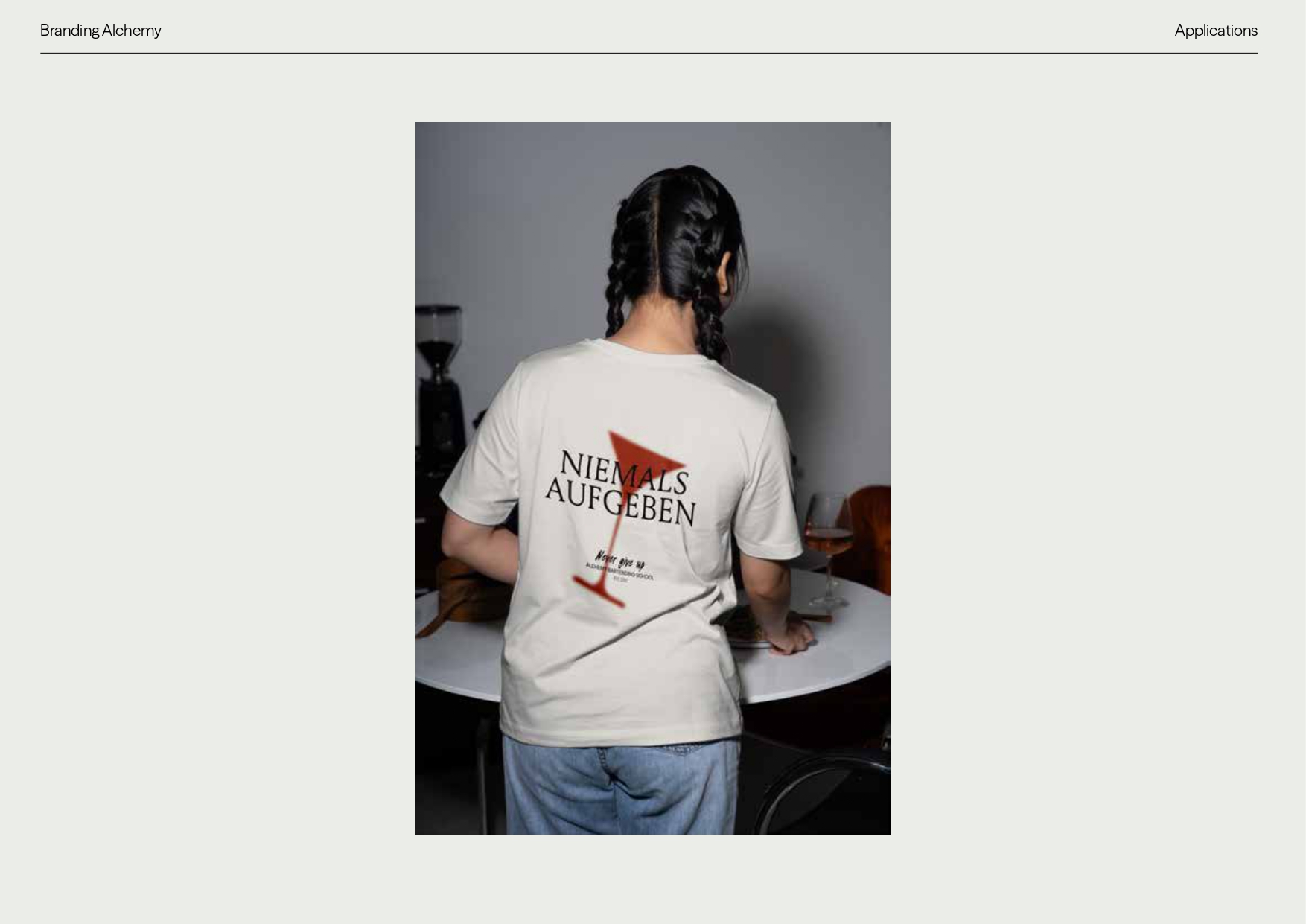 Camiseta con diseño Niemals Aufgeben — aplicación textil Alchemy Bartending School