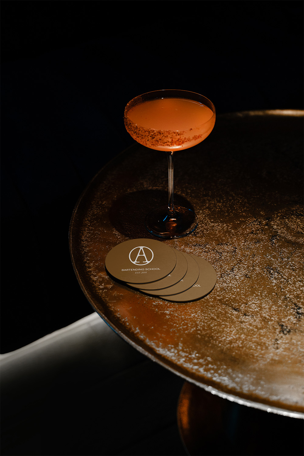Posavasos con logo de Alchemy Bartending School — Aplicaciones de branding por Indigo Estudio