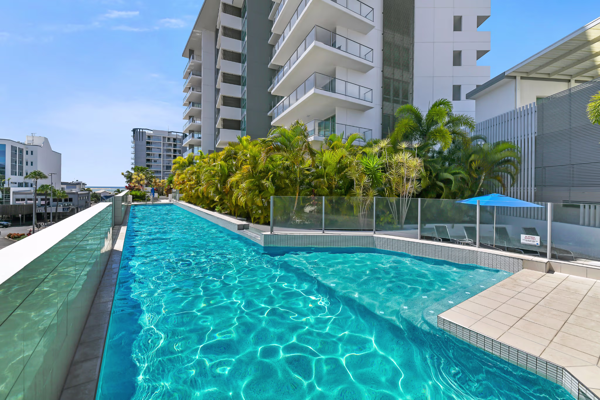 Luxury Sunshine Coast Airbnb management apartment complex with elevated lap pool, tropical landscaping, and modern high-rise design.