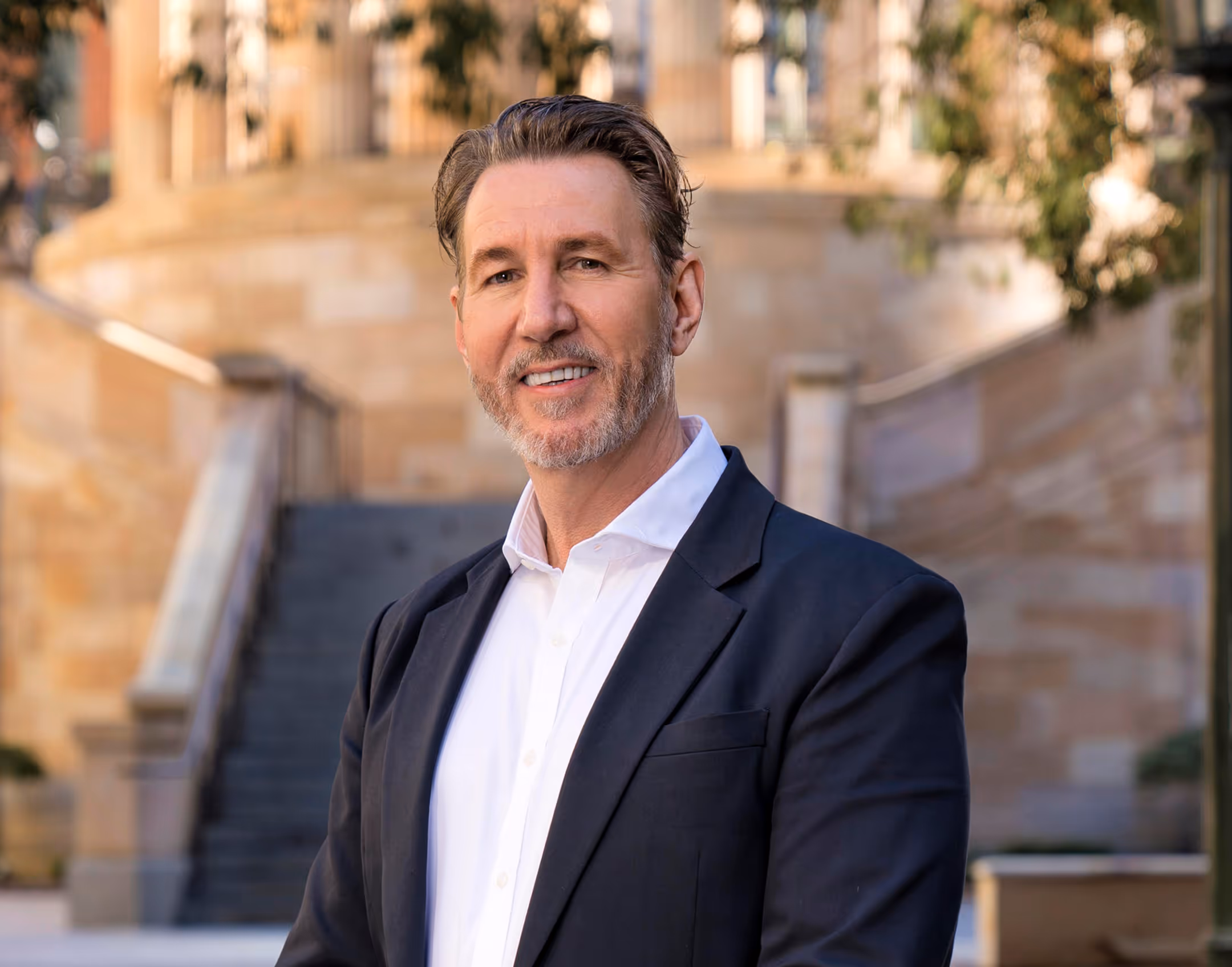 A smiling photo of man wearing the black coat.