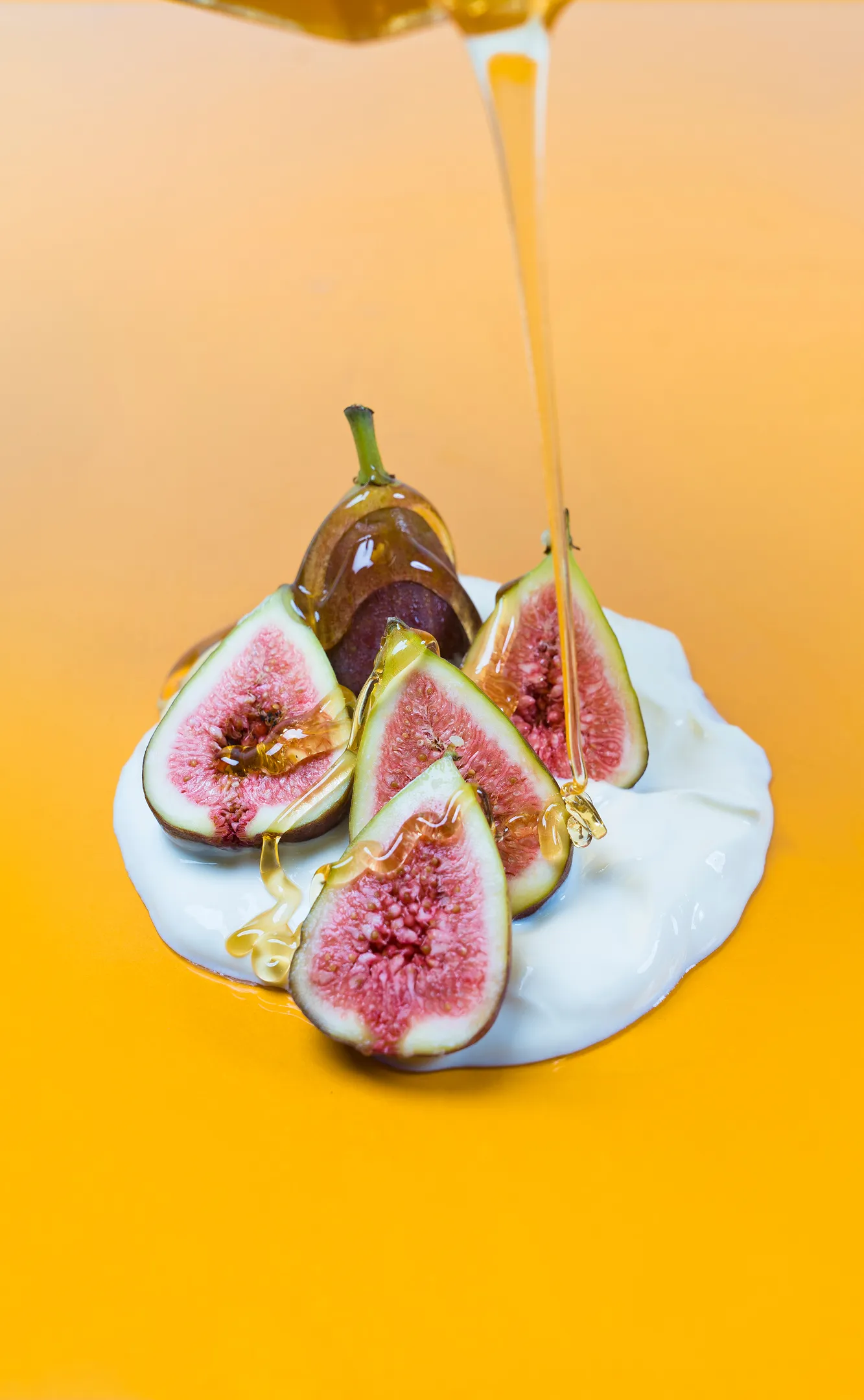 A piece of fruit being dipped into a jar of honey.