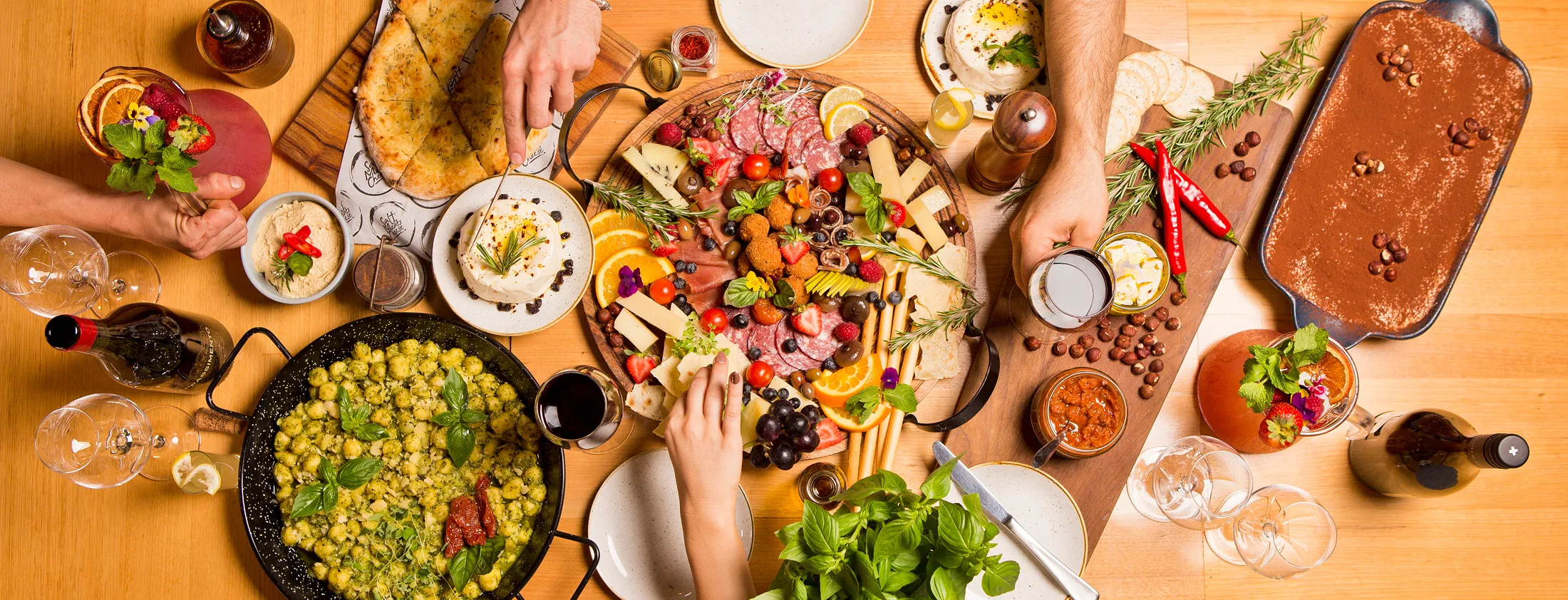 A table filled with plates of assorted fruits, with people sharing a meal.
