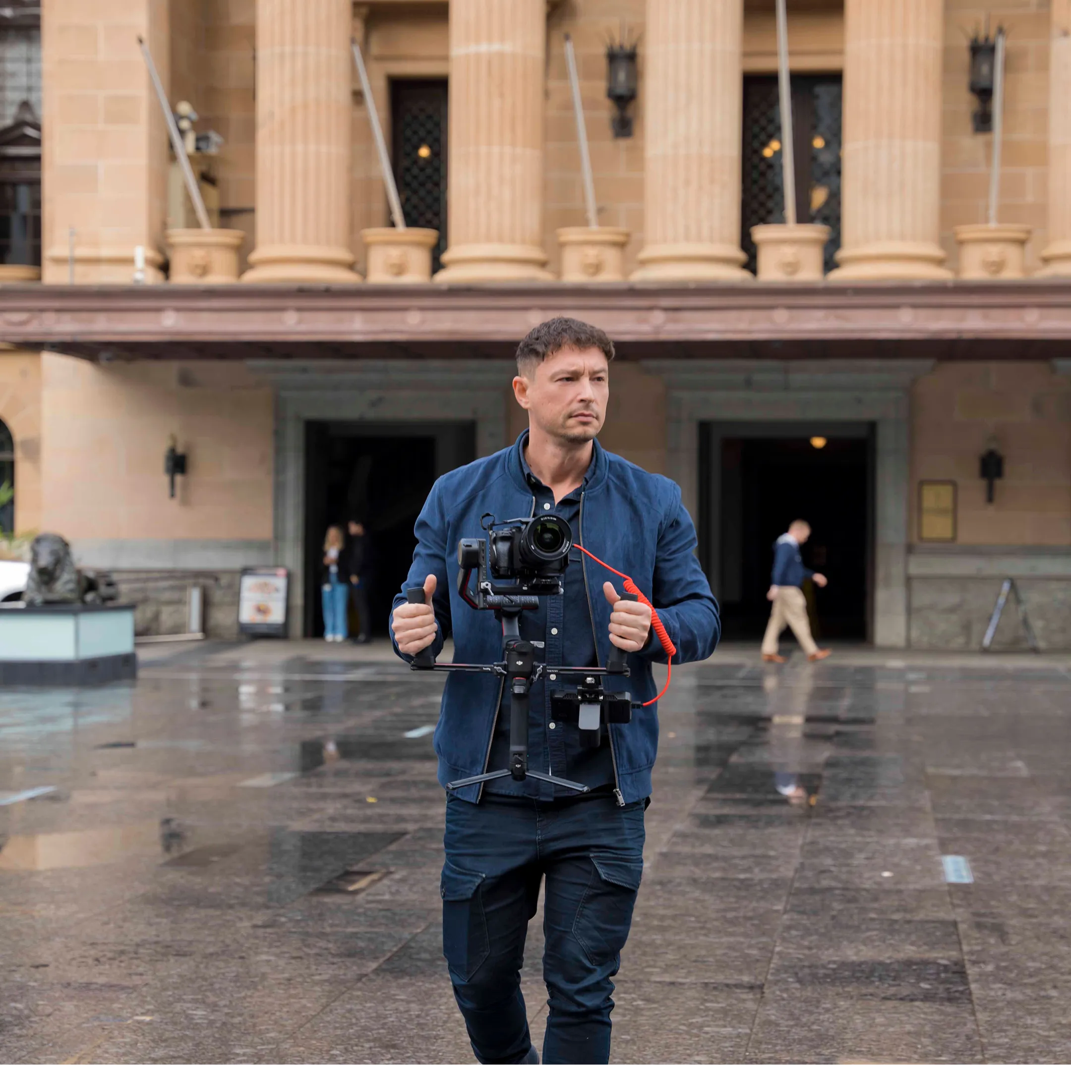 Male videographer with camera shooting on-location in rainy Brisbane weather, showcasing NK Creative's dynamic videography expertise.