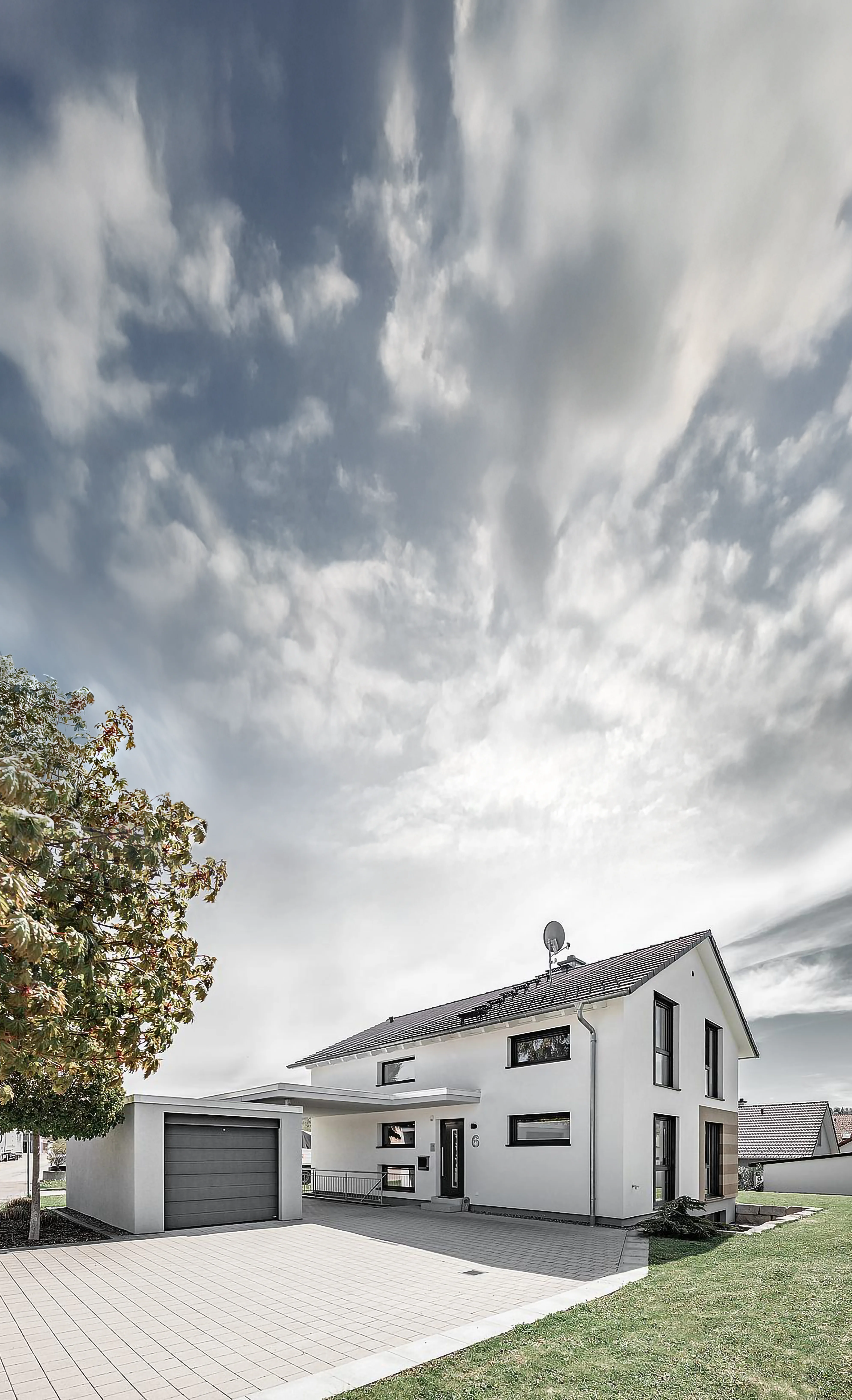 Einfamilienhaus von HAUSER Massivbau mit gepflasterter Hofeinfahrt.