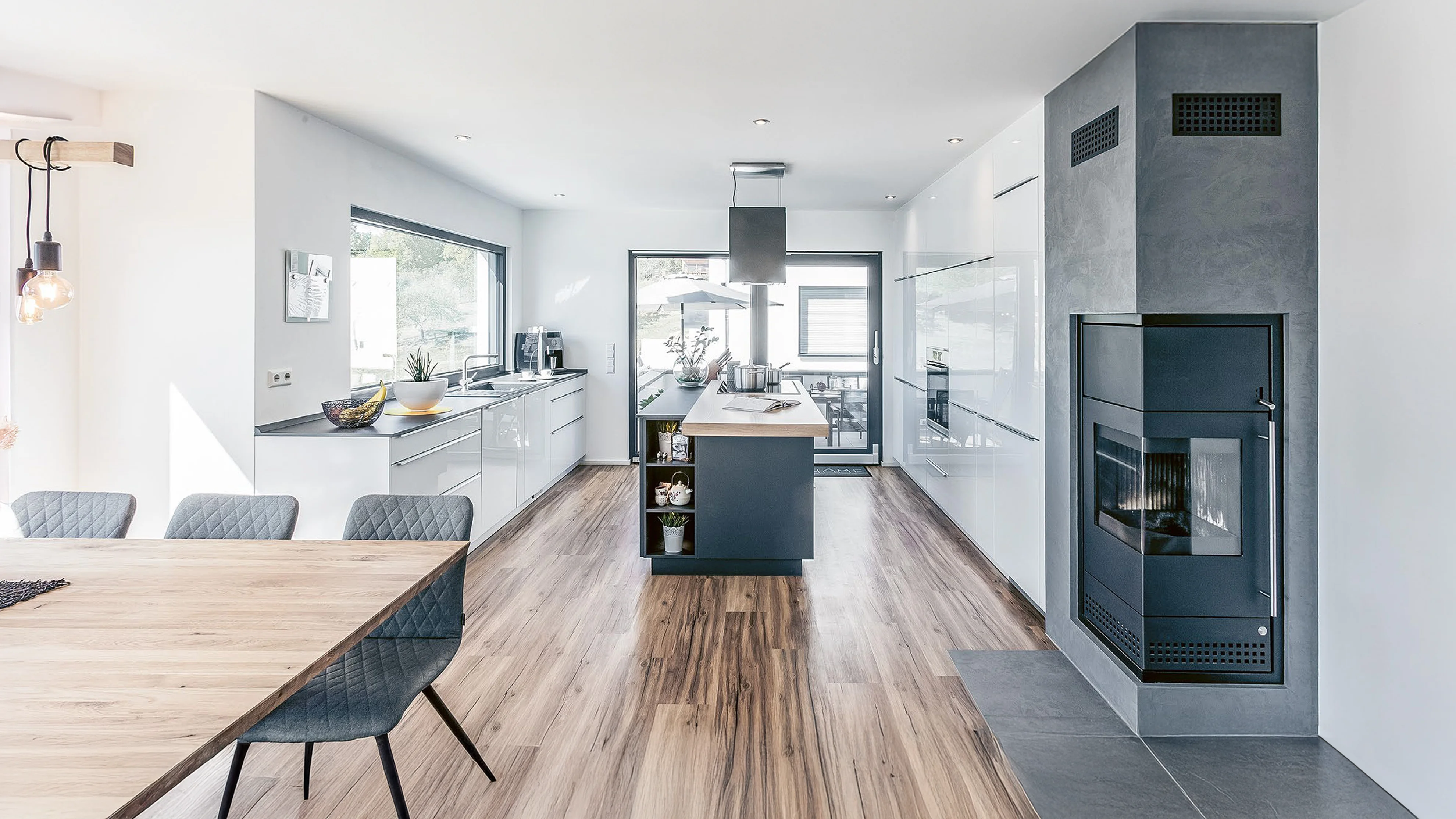 Esszimmer mit Blick auf Küche mit langer Kücheninsel und integriertem Kamin.