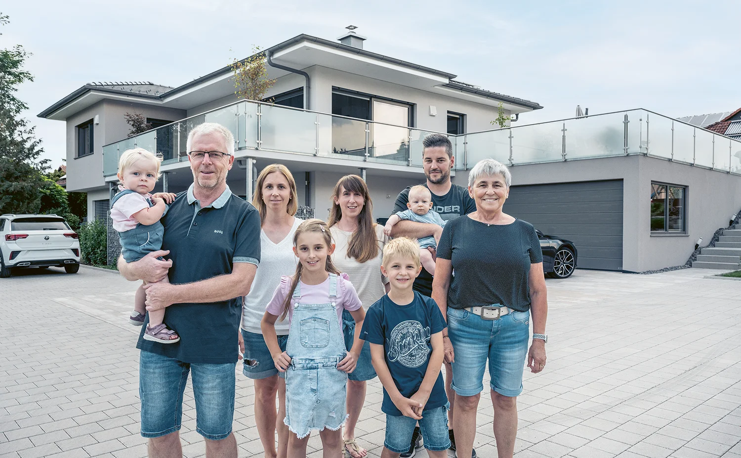 Familie mit Kindern, Ehepartnern und Urenkeln vor ihrem HAUSER-Haus.