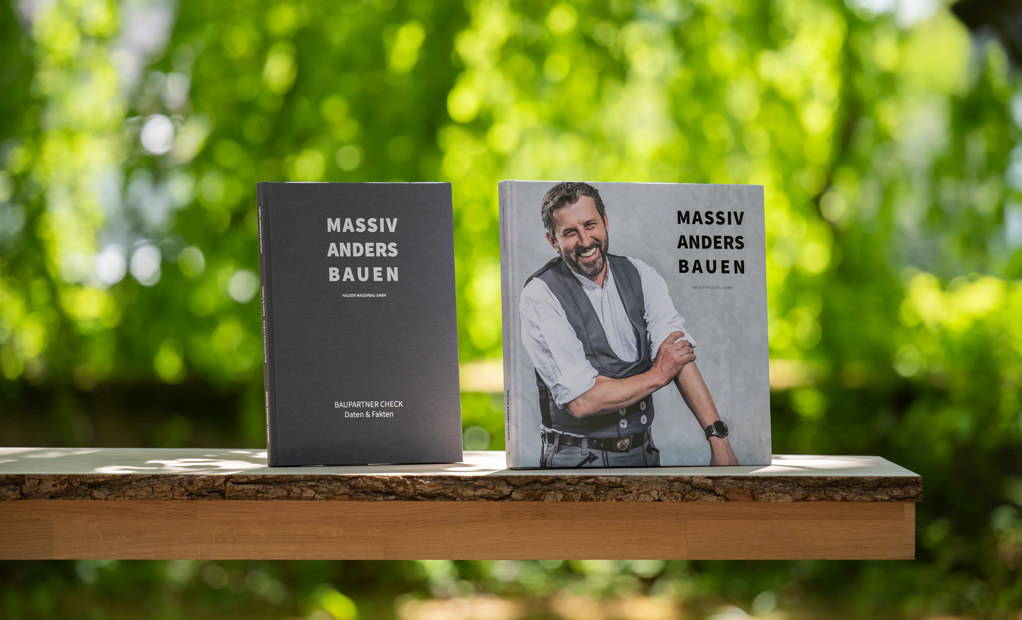 Baupartner-Check und Bildband von HAUSER auf einem Tisch in der Natur.