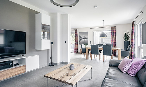 Ansicht Wohnzimmer mit Ledersofa, TV-Board und Esszimmer.