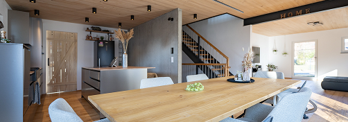 Panoramabild Esstisch aus Holz mit Blick auf Küche, Treppe und Wohnzimmer.