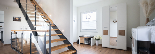 Breite Holztreppe in hellem Flur mit Holzfußboden.