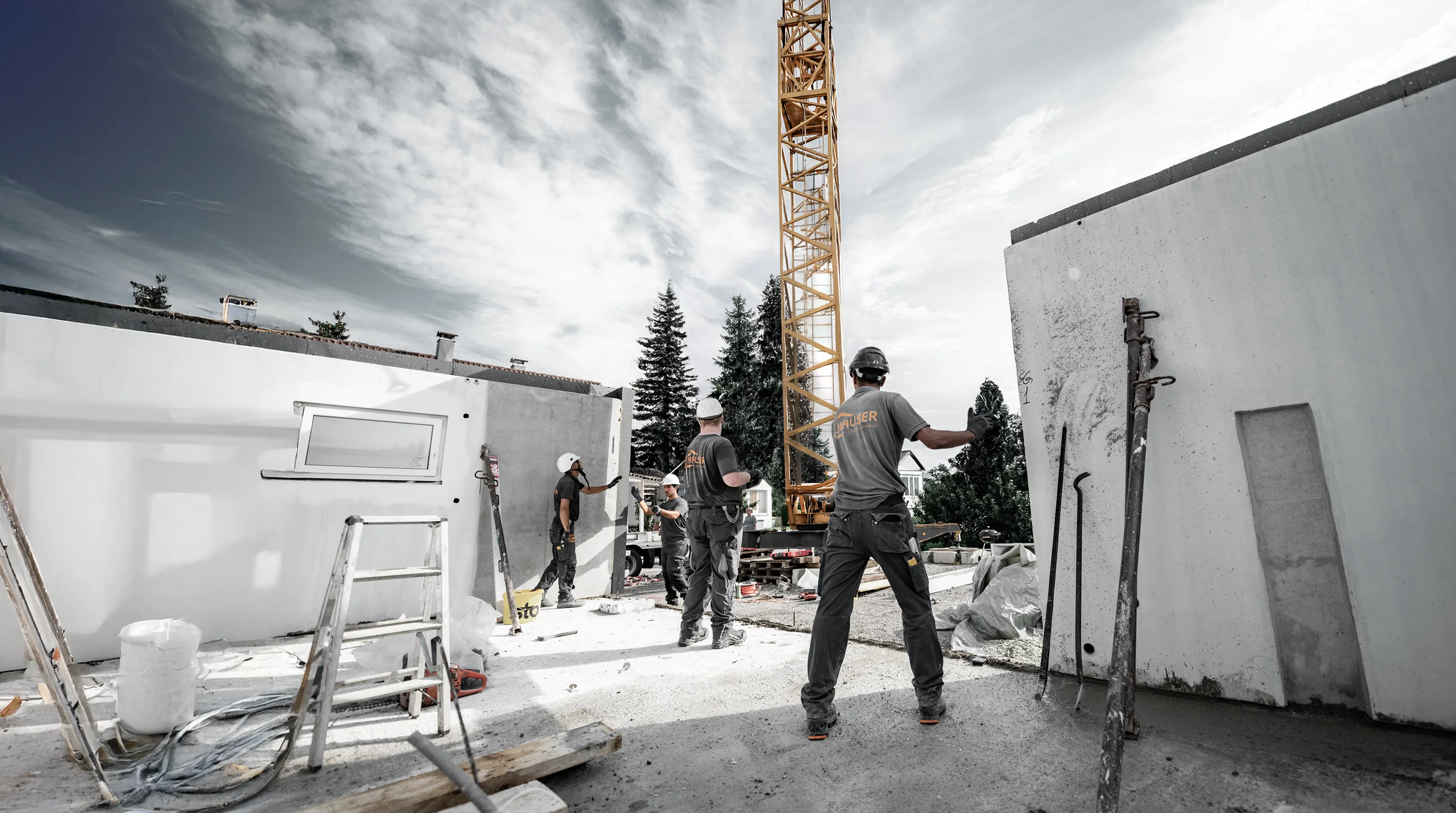 Bauarbeiter auf einer Hausbaustelle mit Kran.