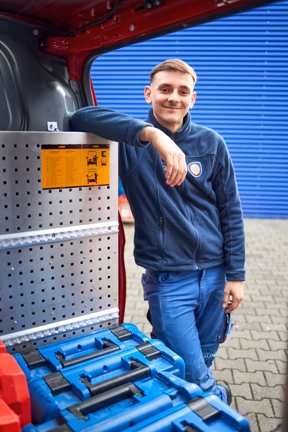 Saling Mitarbeiter am geöffneten Firmenwagen, angelehnt.