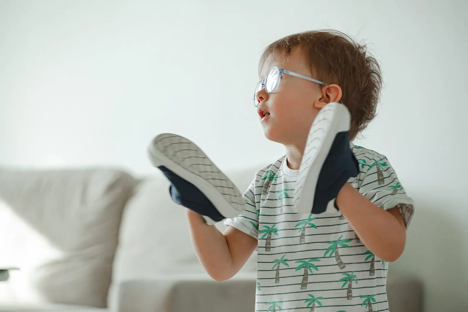 child with glasses with shoes on his hands