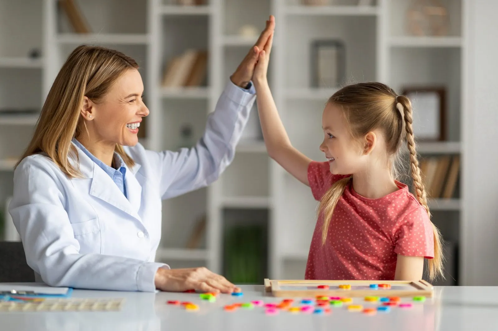 happy professional putting hand toward child client
