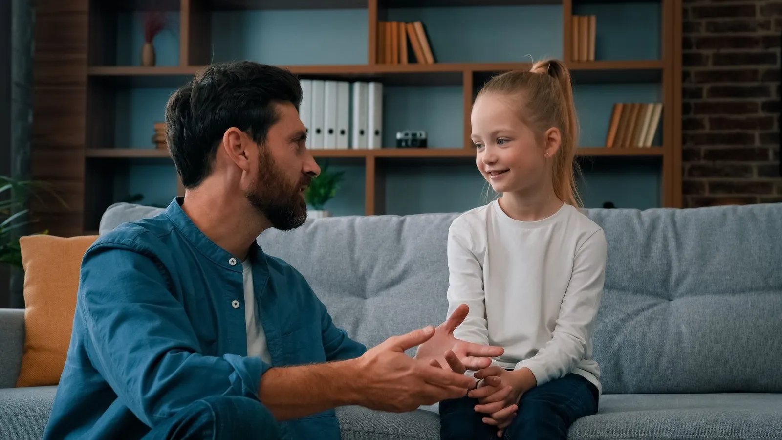 father on floor speaking to daughter on couch