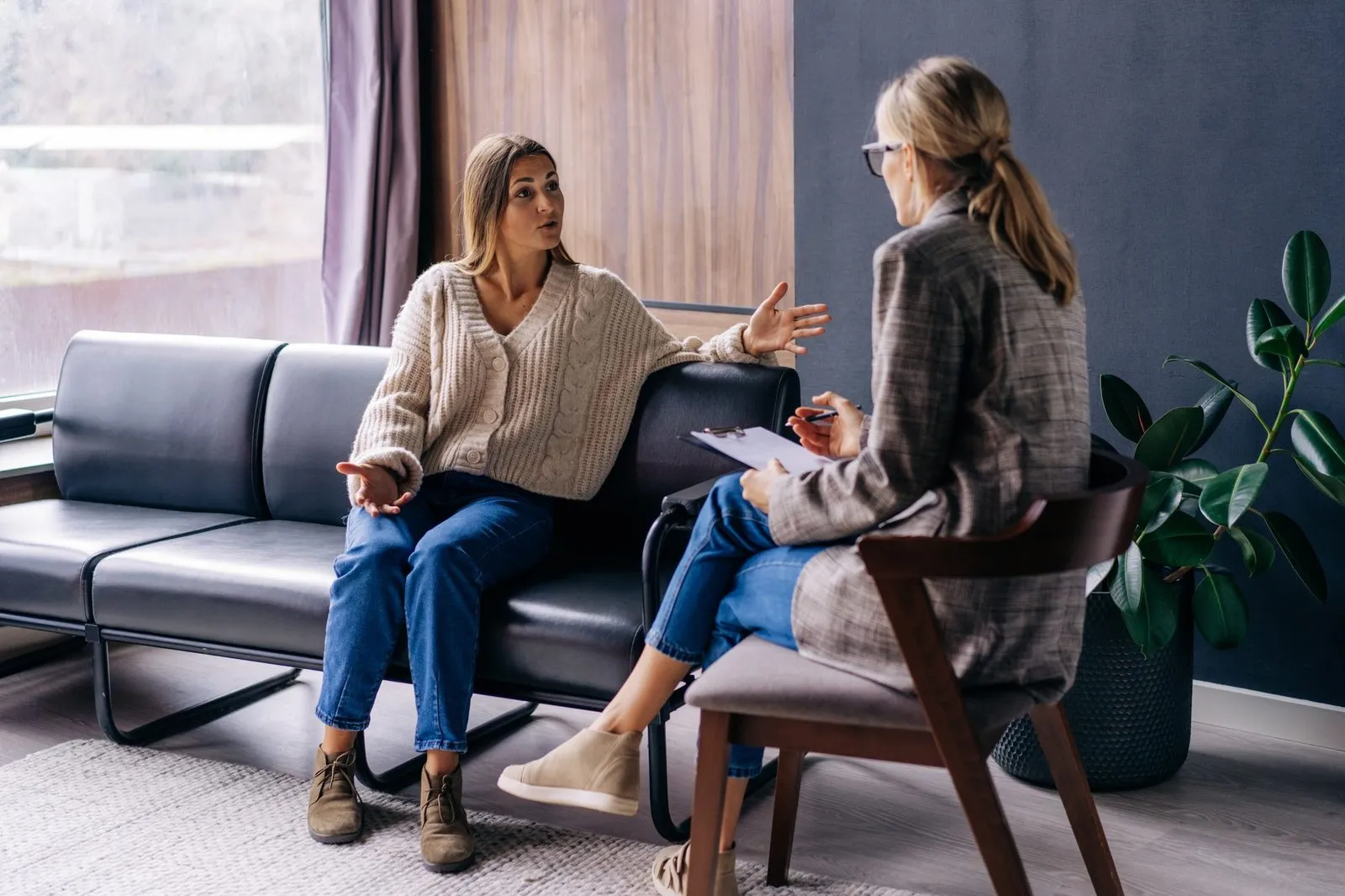 a woman sitting on a couch talking to a woman