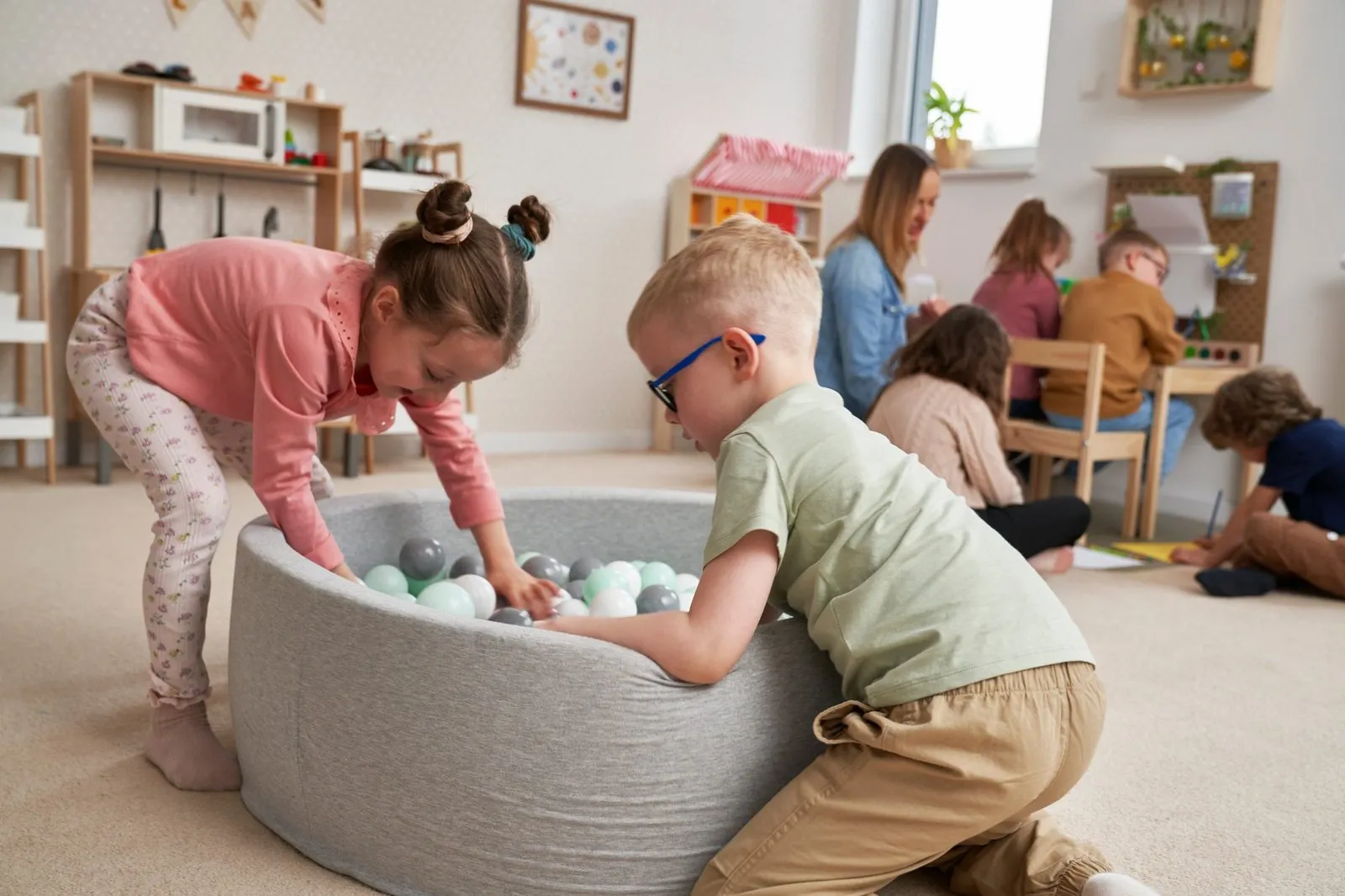 a boy and girl playing with balls in a ball pit