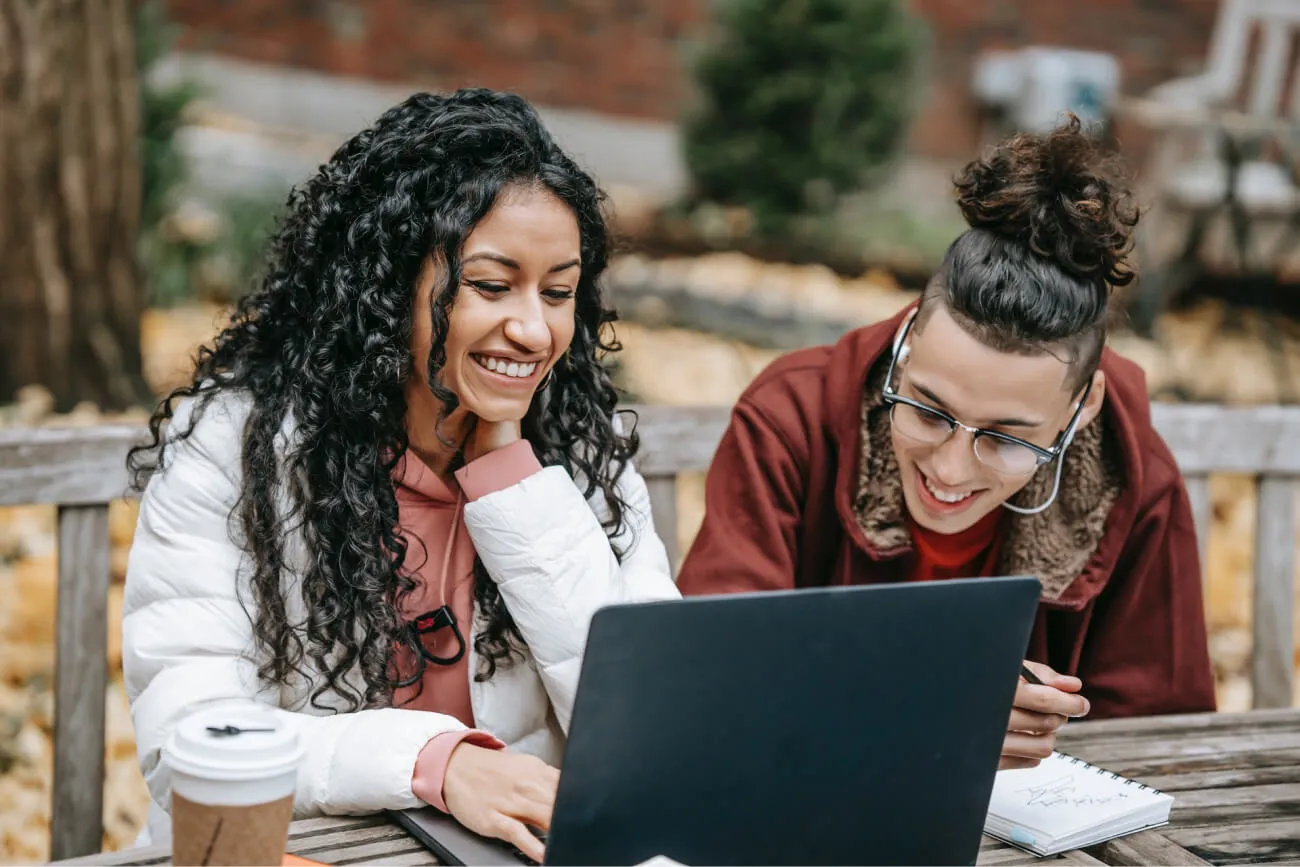a couple of women looking at a laptop