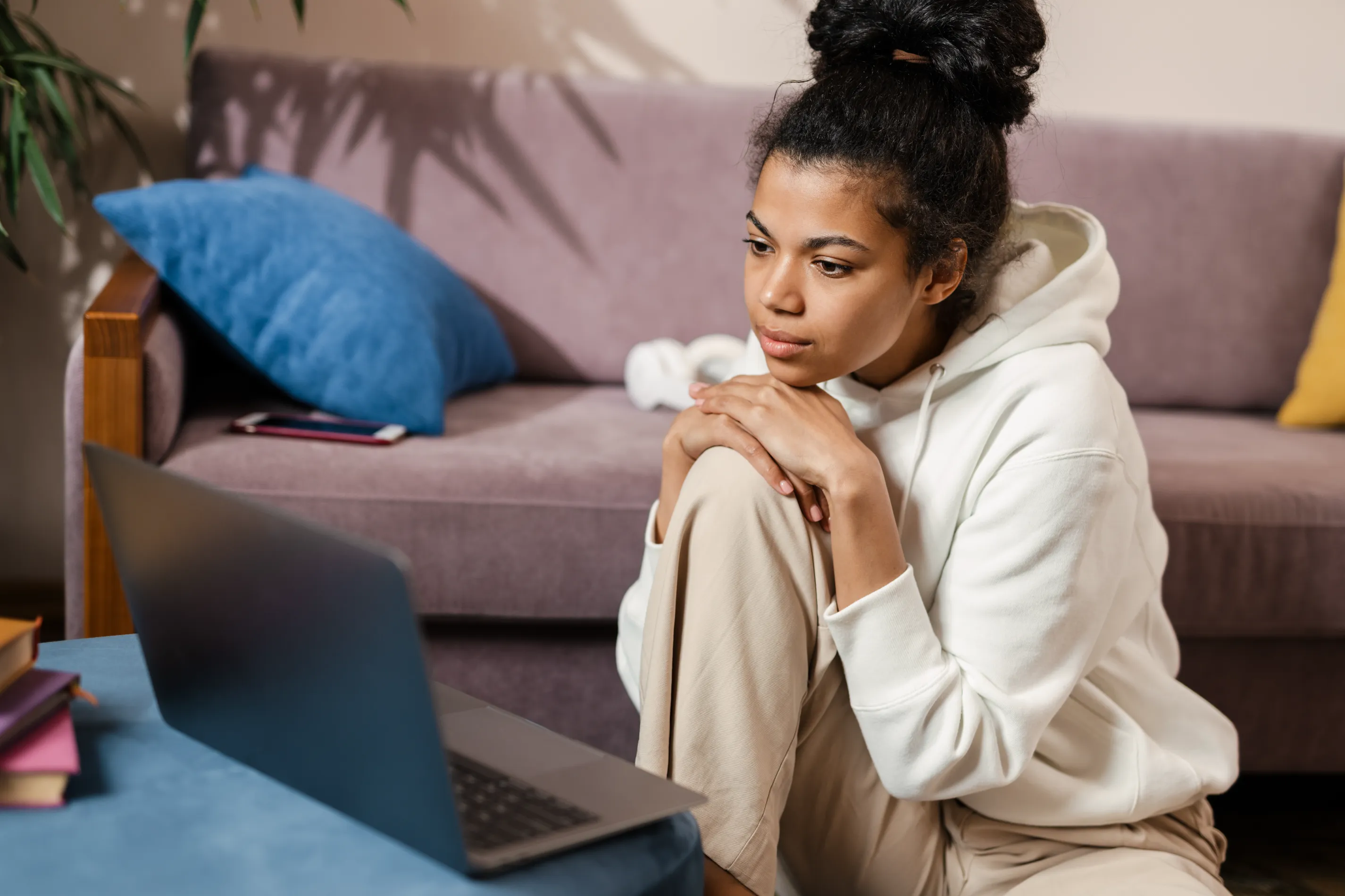 a woman sitting on a couch looking at a laptop