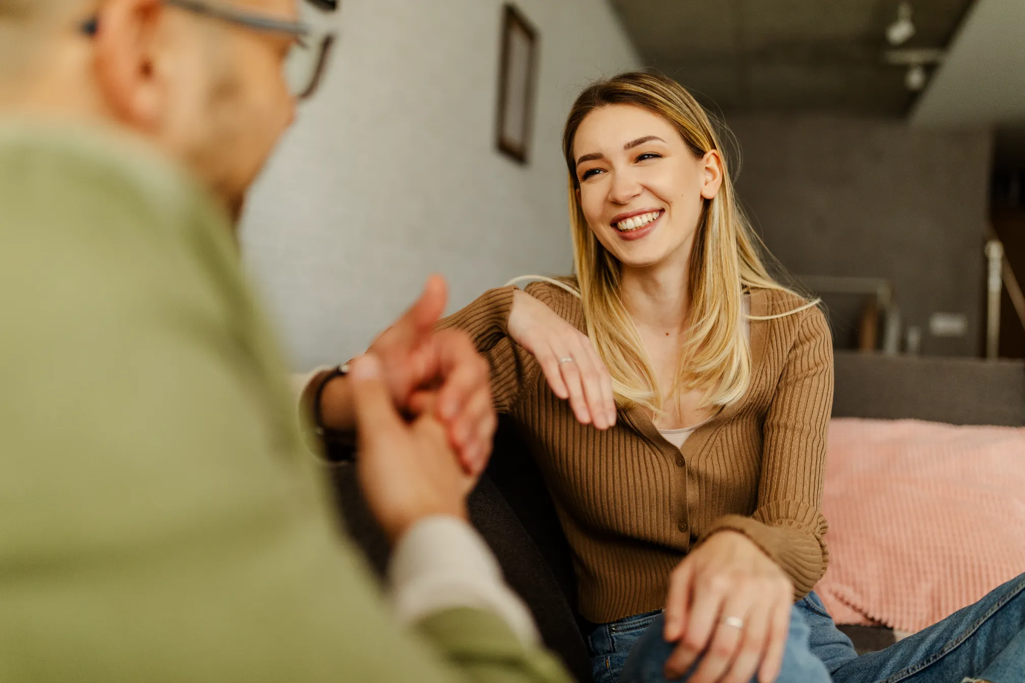 a woman sitting on a couch holding a man's hand