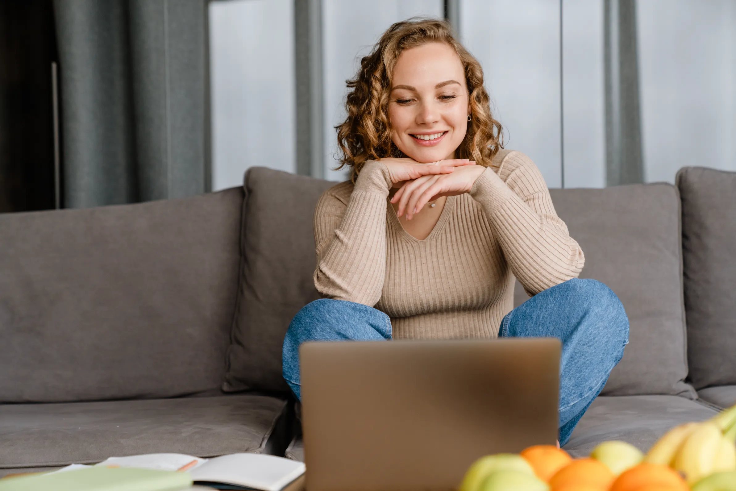 a woman sitting on a couch looking at a laptop