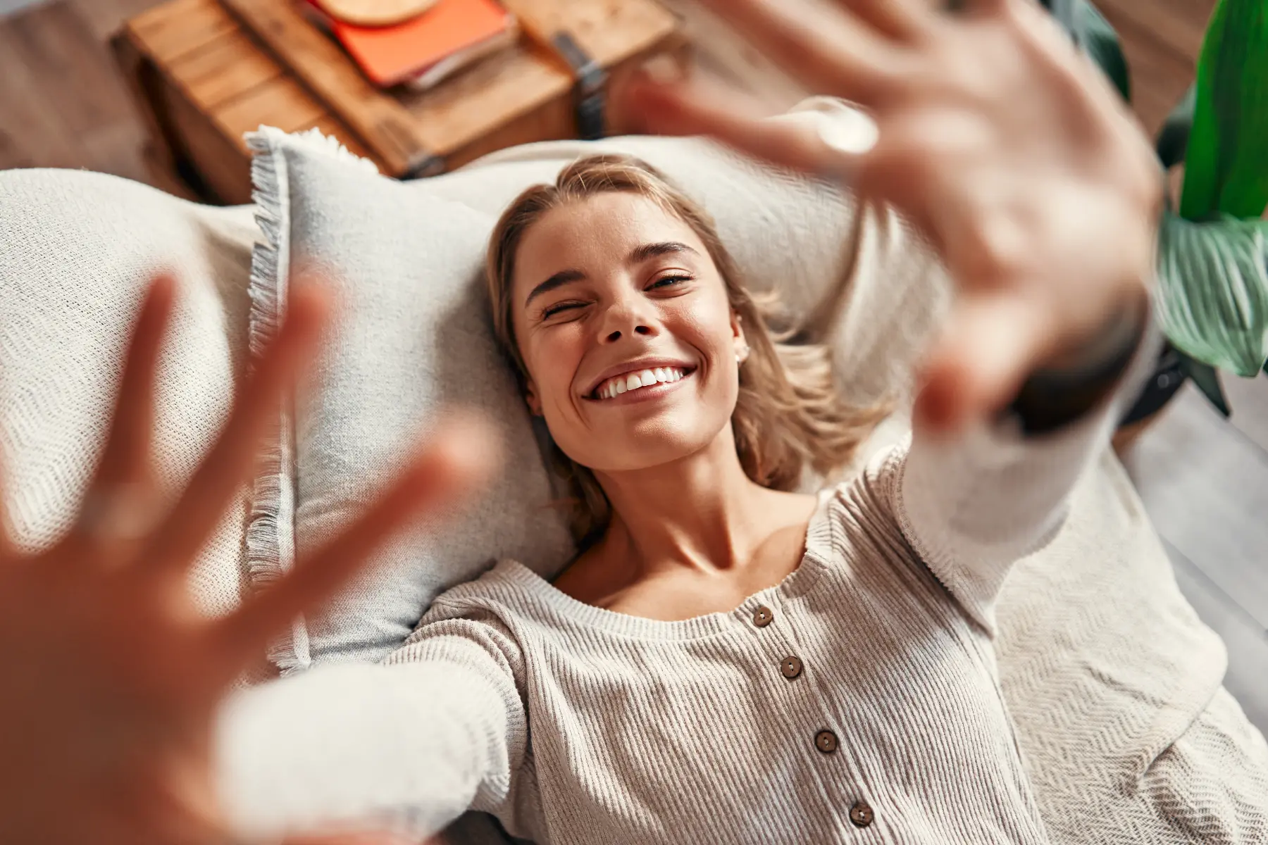 a woman lying on a couch with her hands up