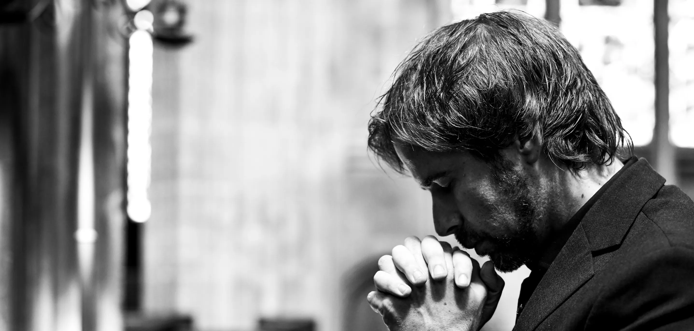 A man in a suit and tie is praying.