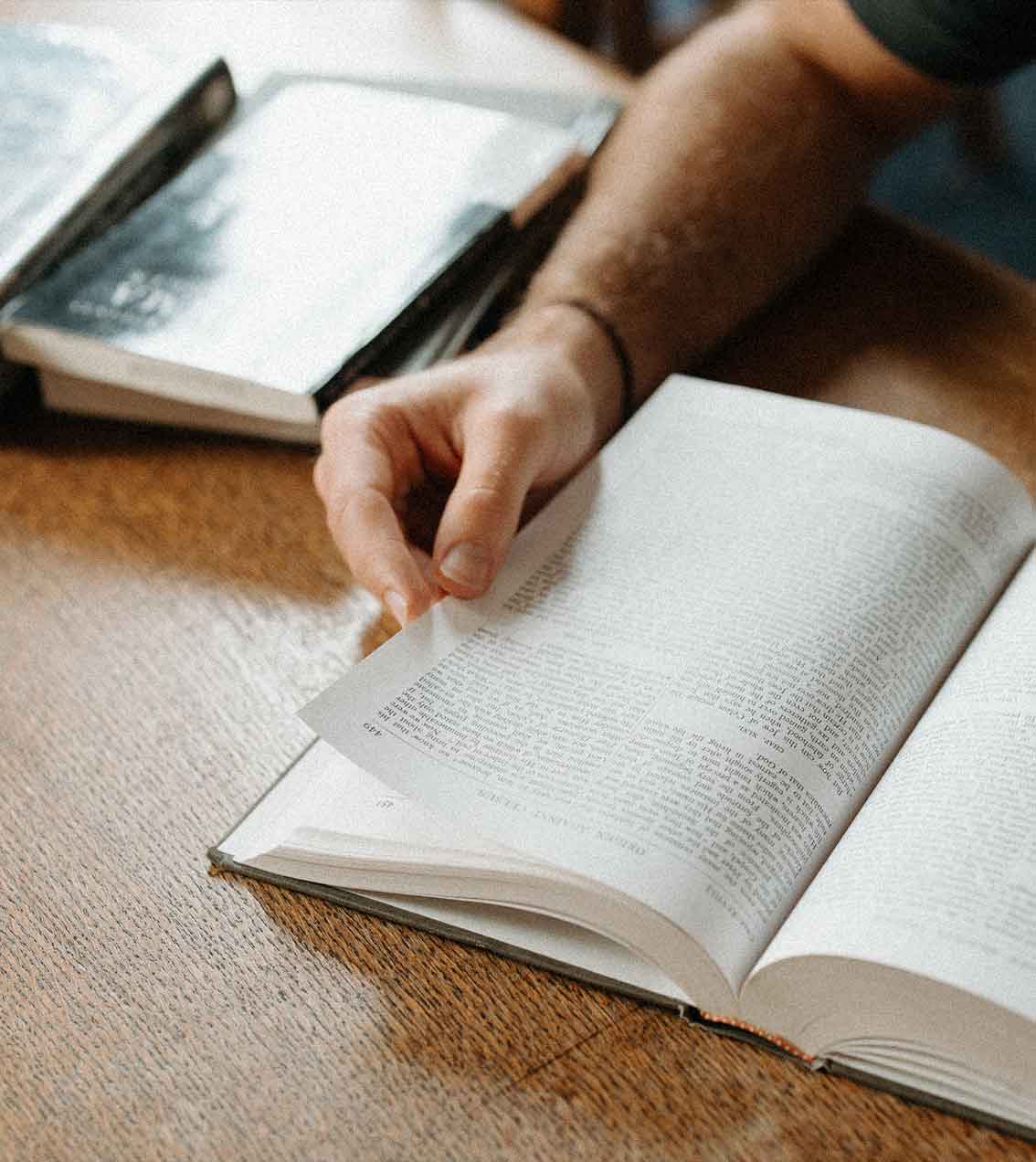 A person is reading a book on a table.