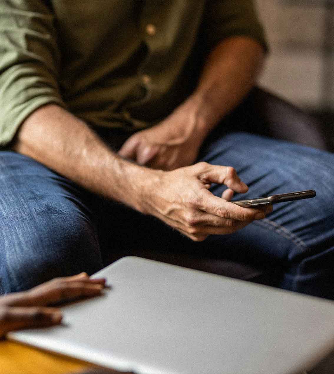A man sitting on a couch using a cell phone.