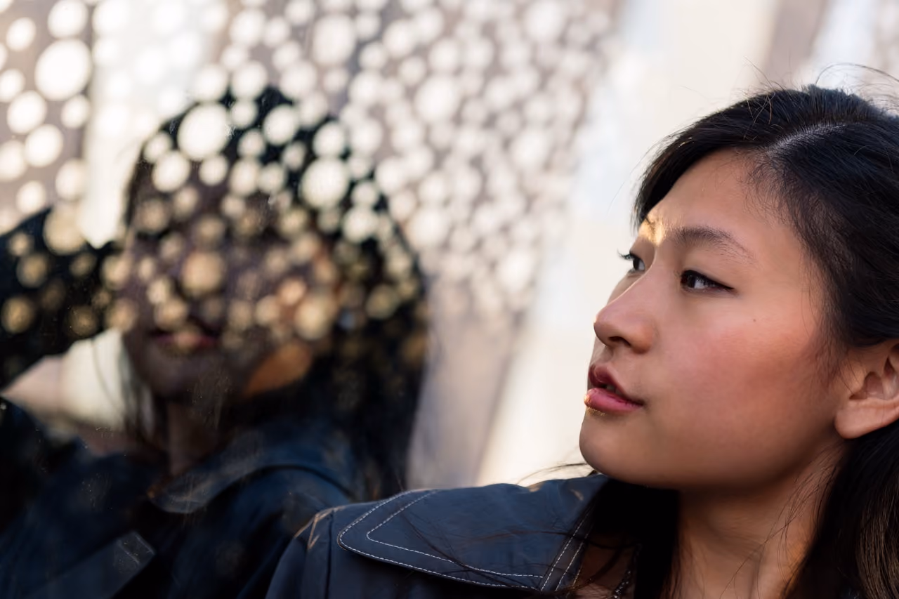 Person looking off into the distance with their reflection behind them
