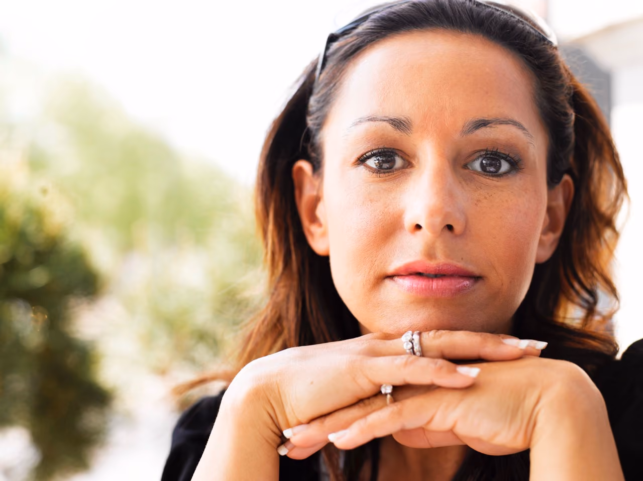 Person looking directly at camera with hands clasped under their chin