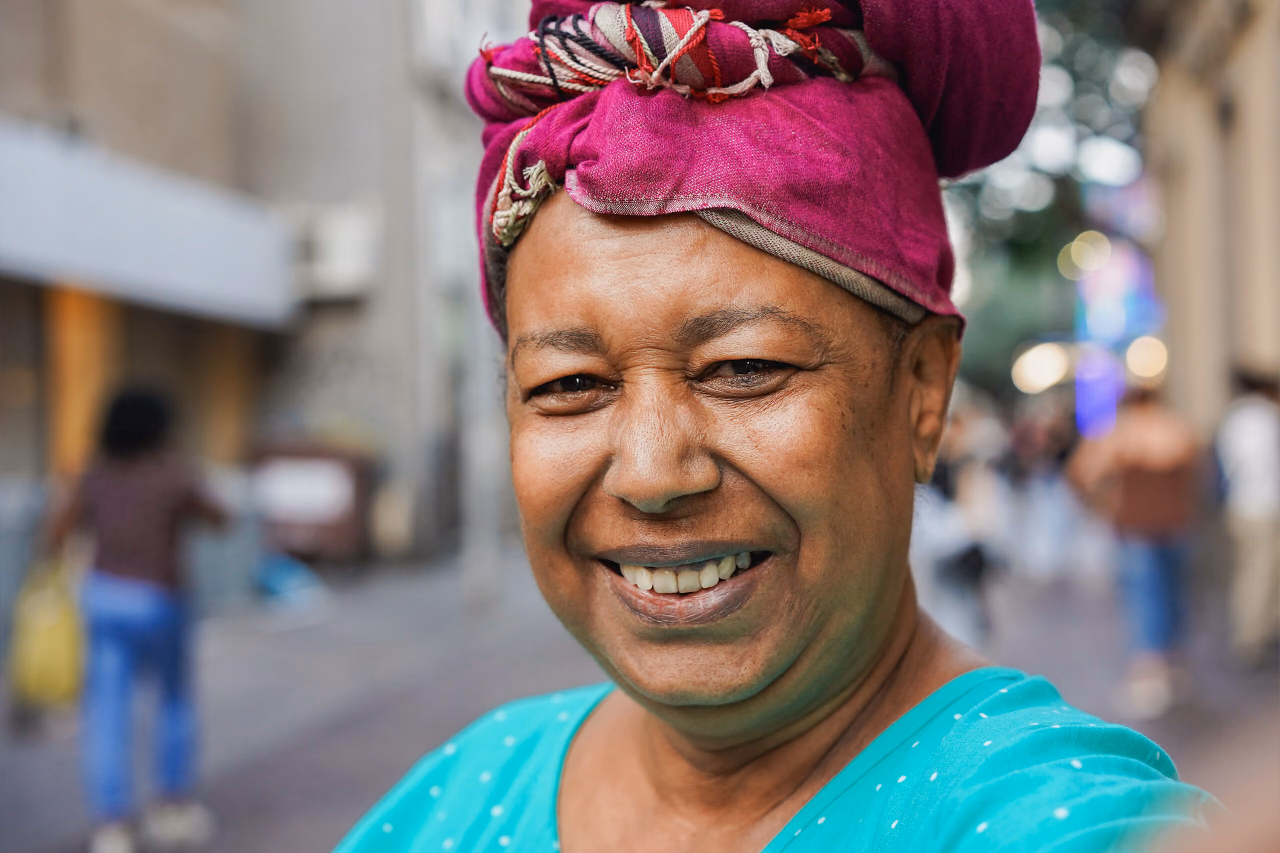 Person smiling and looking directly at the camera while standing outside