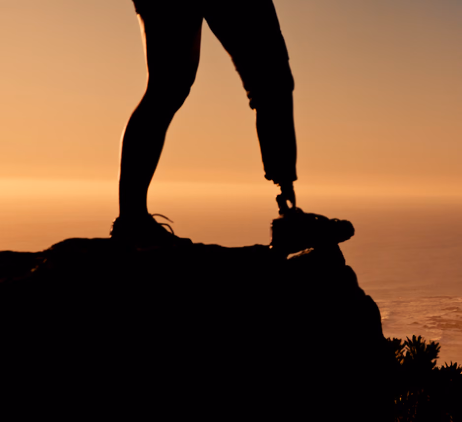 Person with a carbon fiber prosthetic leg standing on a cliff edge overlooking the landscape
