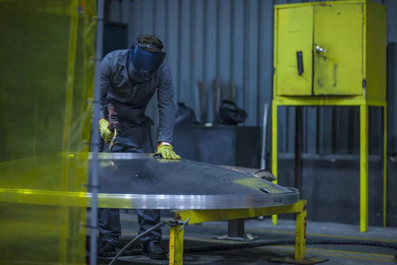 Worker welding metal in factory.