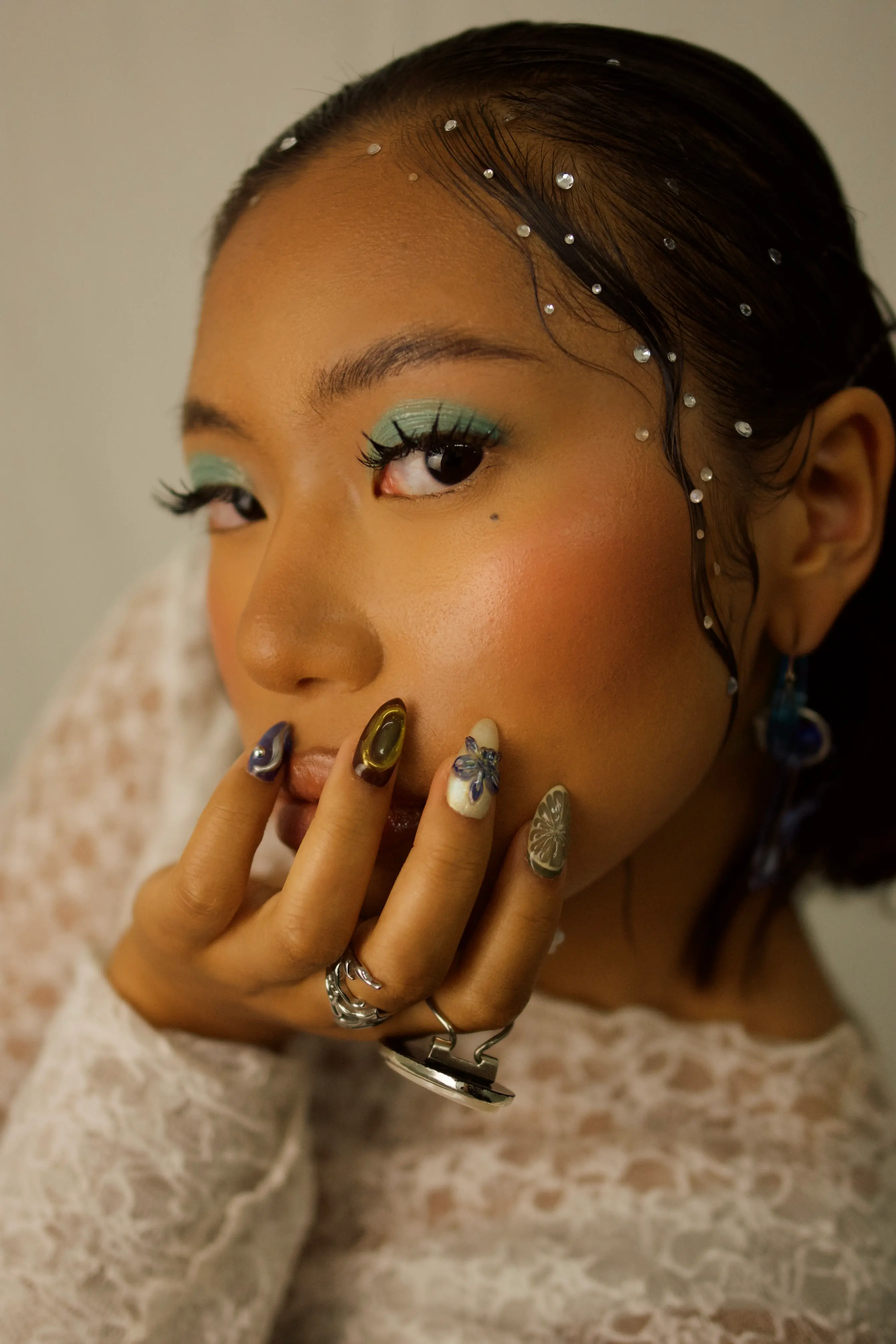 Nahaufnahme einer Frau mit funkelndem Augen-Make-up und auffälligem Nageldesign im Beauty-Studio I AM A PRIORITY.