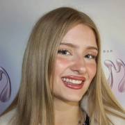 Glückliche Kundin mit blondem Haar vor dem I AM A PRIORITY Logo – Kundenbewertungsporträt