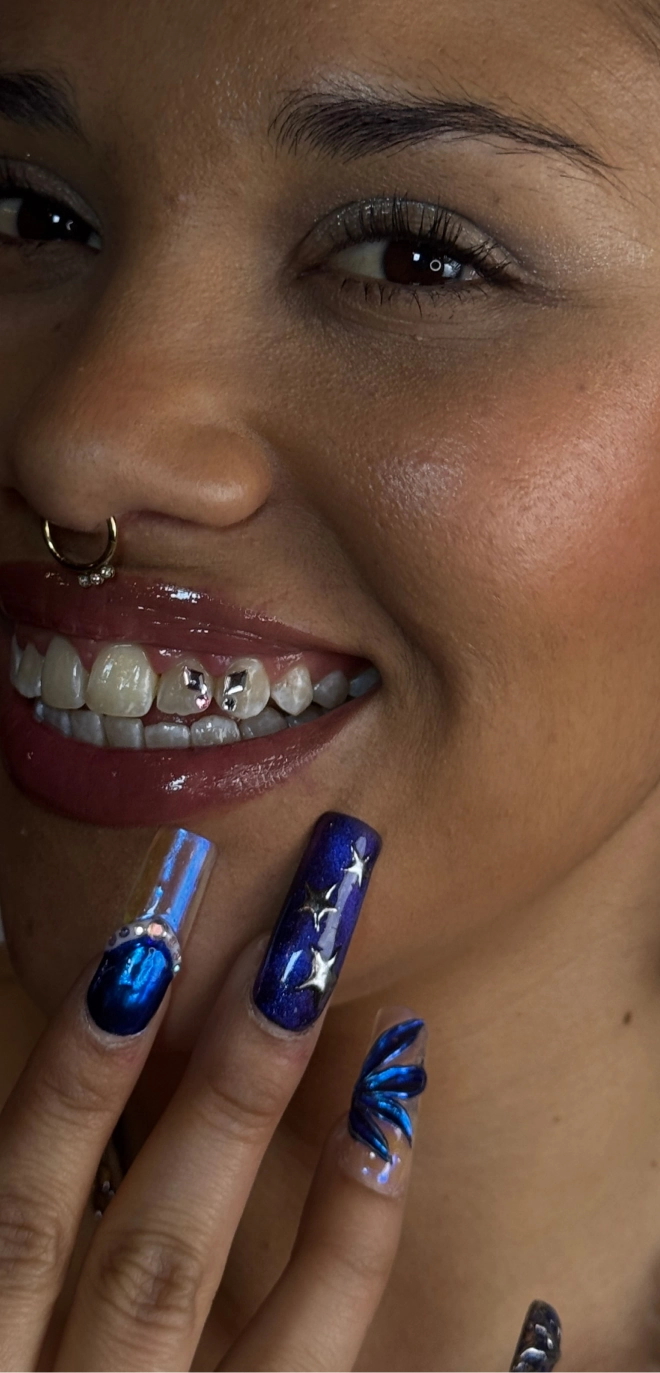 Selbstbewusstes Lächeln mit Tooth Gems und glamourösen blauen Nägeln