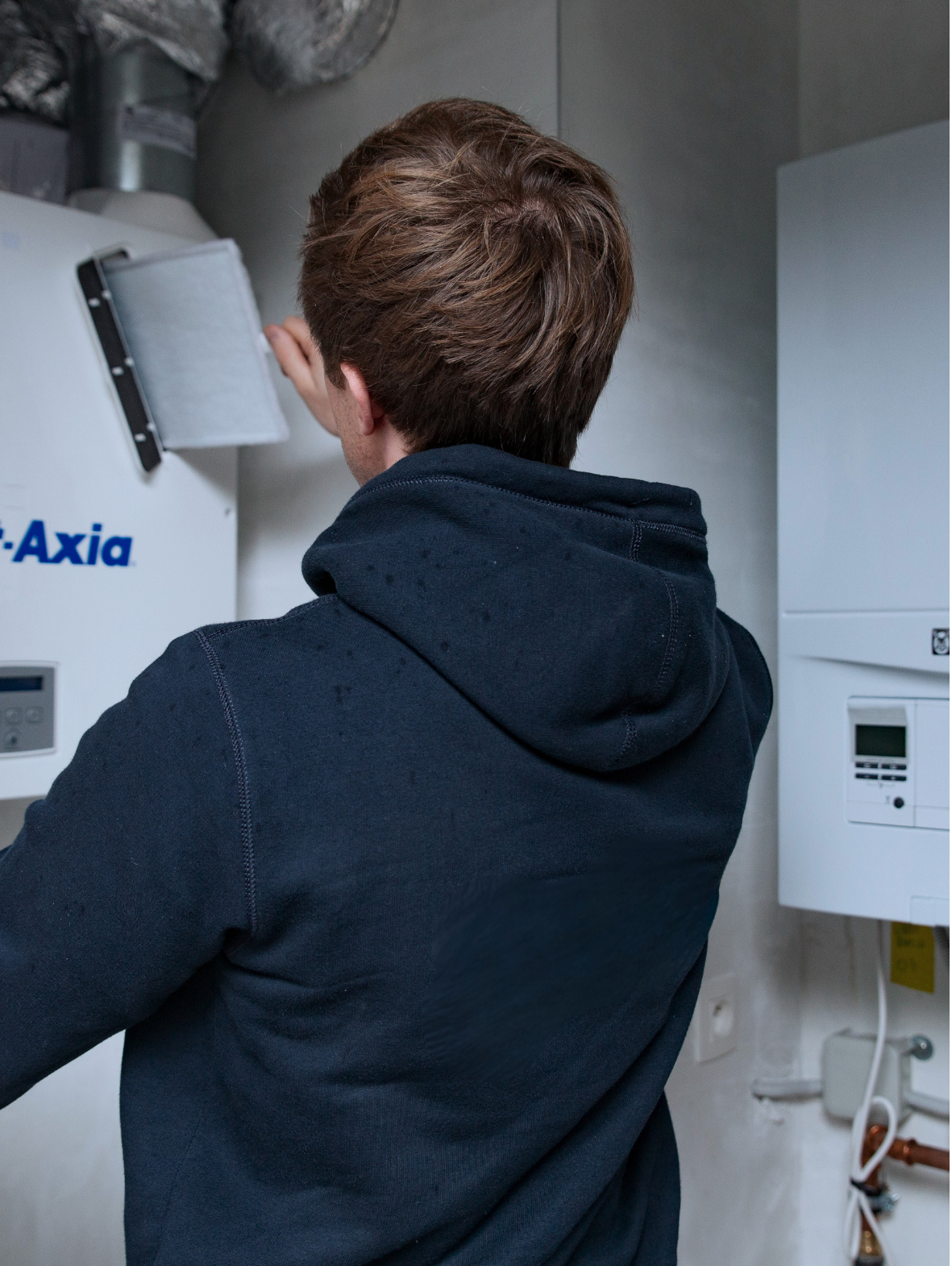 Een man doet een instelling aan een ventilatiesysteem, geplaatst door Juvah.