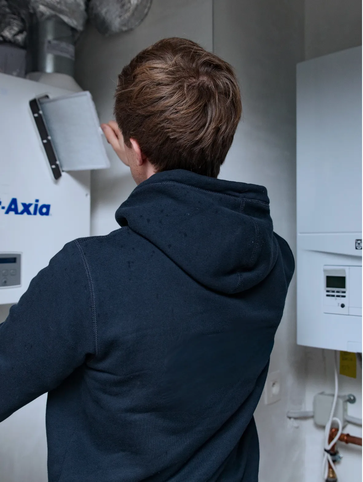 Een man doet een instelling aan een ventilatiesysteem, geplaatst door Juvah.