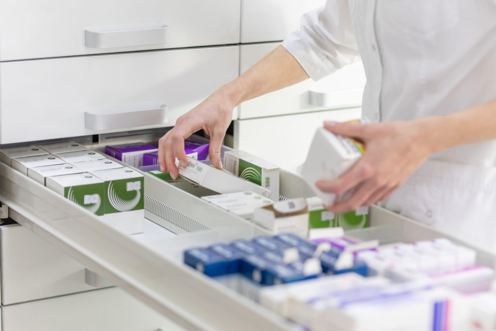 A pharmacist retrieving medication from a drawer