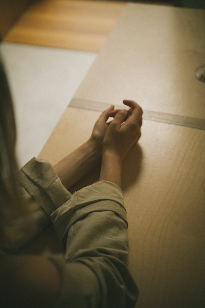Patients hands clasped together leaning on table