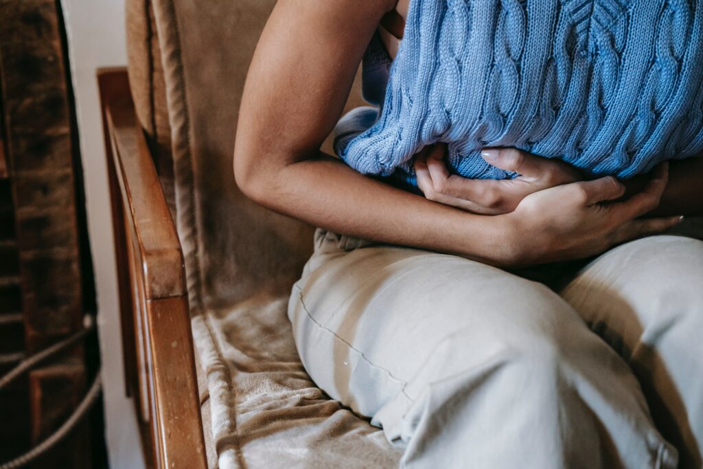 A woman sitting on a chair clutches her abdomen in pain