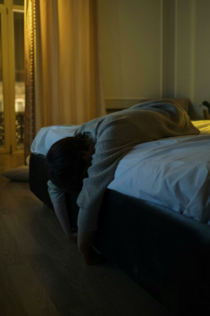 A person hanging off the edge of the bed looking very tired