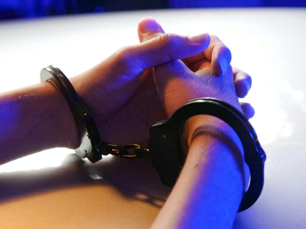 An arrested person's hands with handcuffs on their wrist