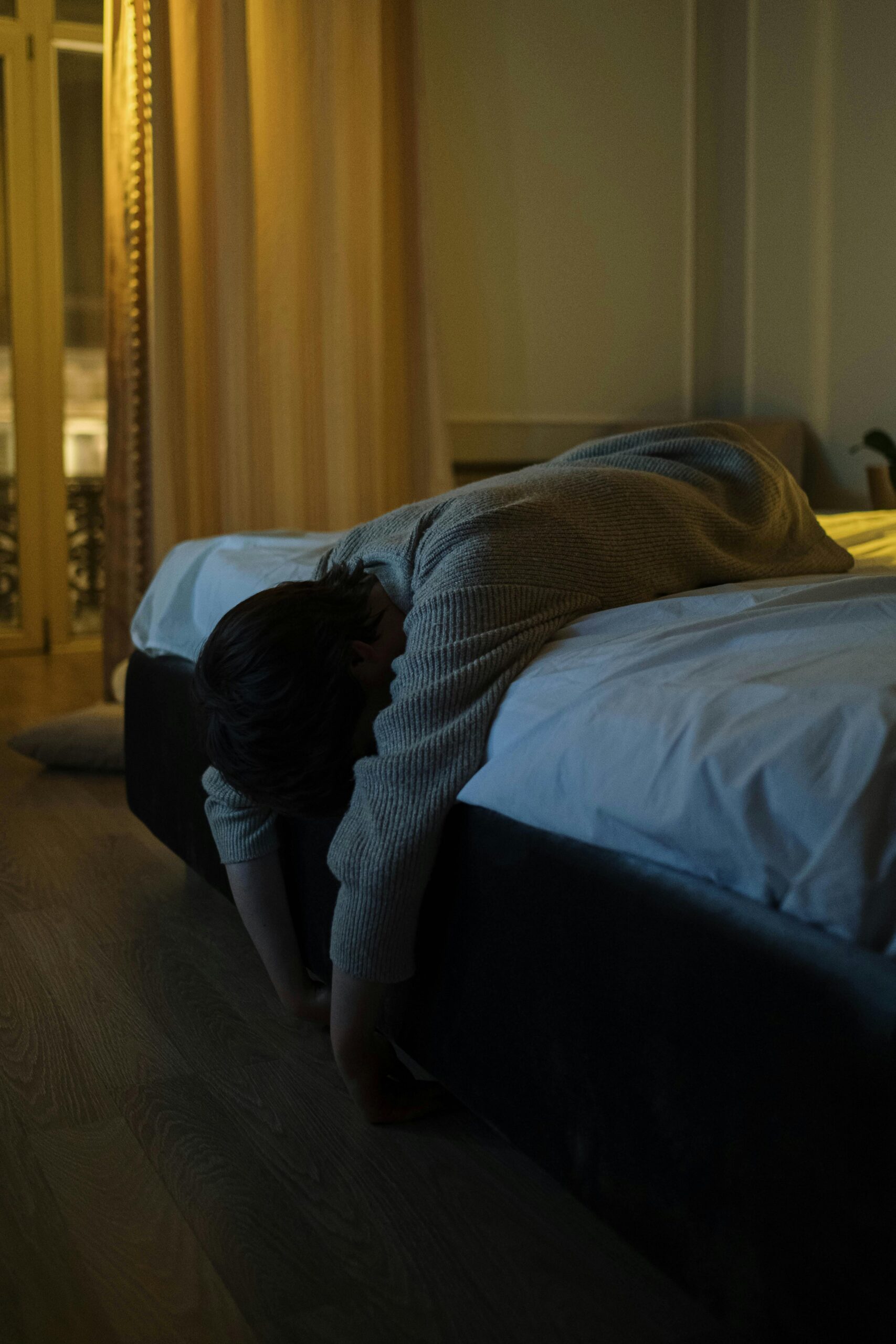 ADHD and Insomnia - a person lying on a bed with their head and arms drooping over the side
